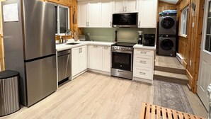 Een kleine keuken met houten kastjes, een roestvrijstalen koelkast, een magnetron, een oven en een wasmachine.