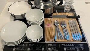 A kitchen counter with various utensils, plates, and a kettle.