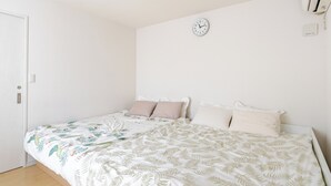 A bedroom with two beds, a clock on the wall, and an air conditioning unit.