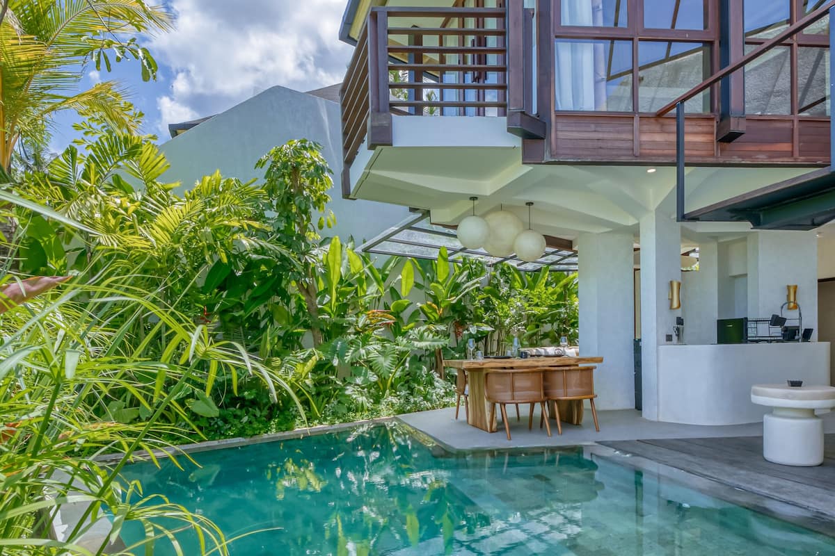 A modern house with a swimming pool surrounded by lush tropical plants.
