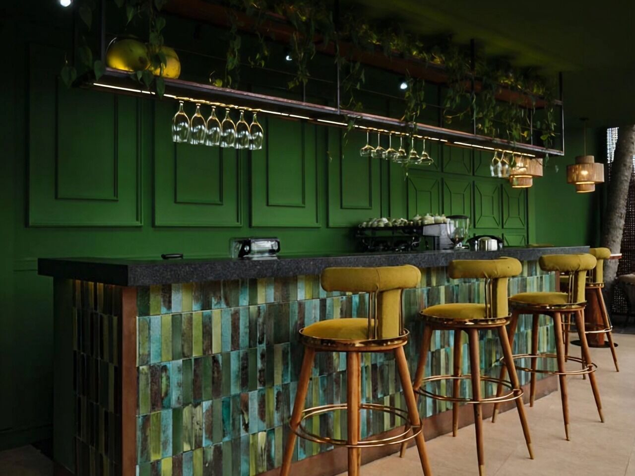 A bar area with green walls, a tiled backsplash, and bar stools.