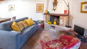 Ein Wohnzimmer mit einem blauen Sofa, einem roten Sessel, einem Kamin und einem Fernseher.