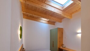 A small, well-lit bedroom with a skylight, a bed, a green wardrobe, and a wooden bench. - Roseto Apartments Trilo 2 by Interhome (Roseto degli Abruzzi)