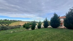 A grassy yard with a fence, trees, and a building with a red roof. - Roseto Apartments Trilo 2 by Interhome (Roseto degli Abruzzi)