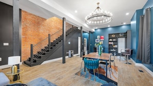 A modern living room with a staircase, a dining area, and a chandelier. - Artsy Creative Haven Home St. Louis Art District (St. Louis)