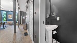 A modern interior with a hallway leading to a bathroom, featuring a sink and toilet. - Artsy Creative Haven Home St. Louis Art District (St. Louis)