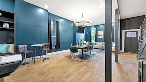 A modern living room with a dining area, a staircase, and a large window. - Artsy Creative Haven Home St. Louis Art District (St. Louis)