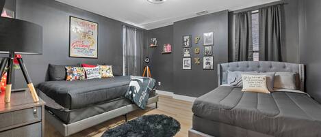 Une chambre moderne avec deux lits, un bureau et un tapis noir.