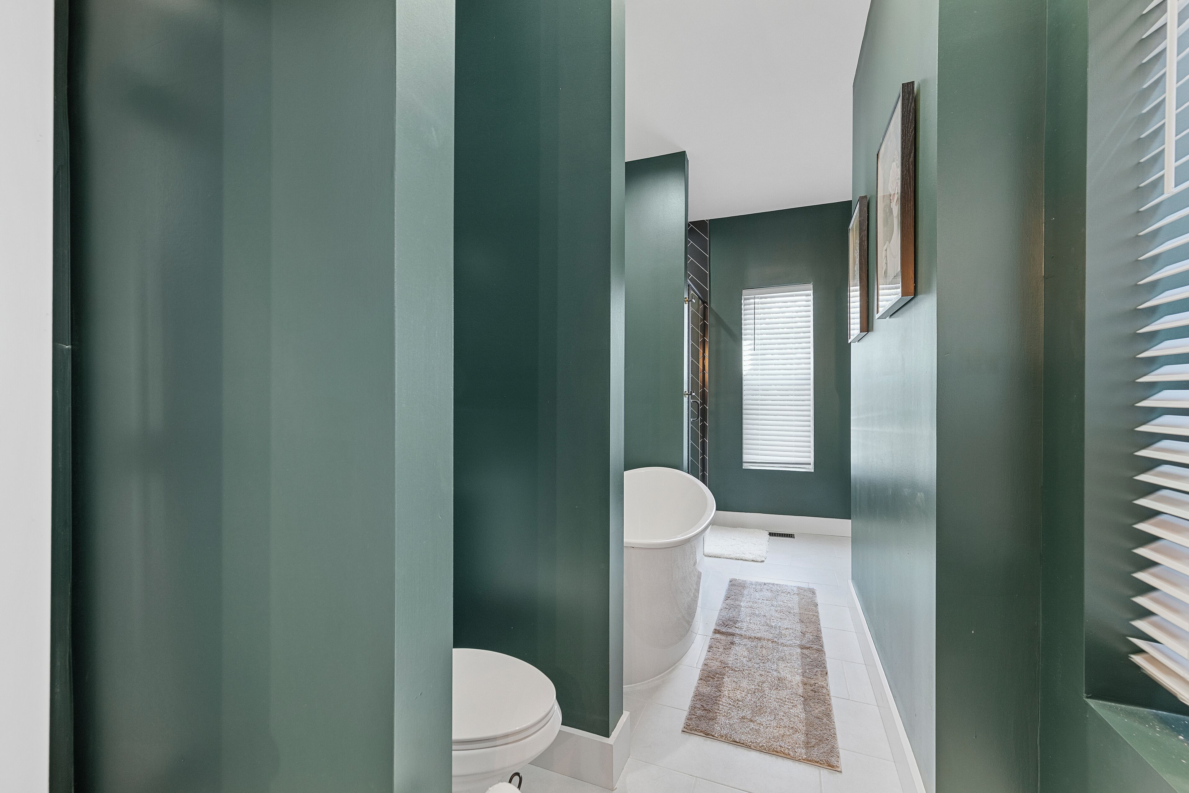 A narrow hallway leading to a bathroom with a toilet, sink, and bathtub.