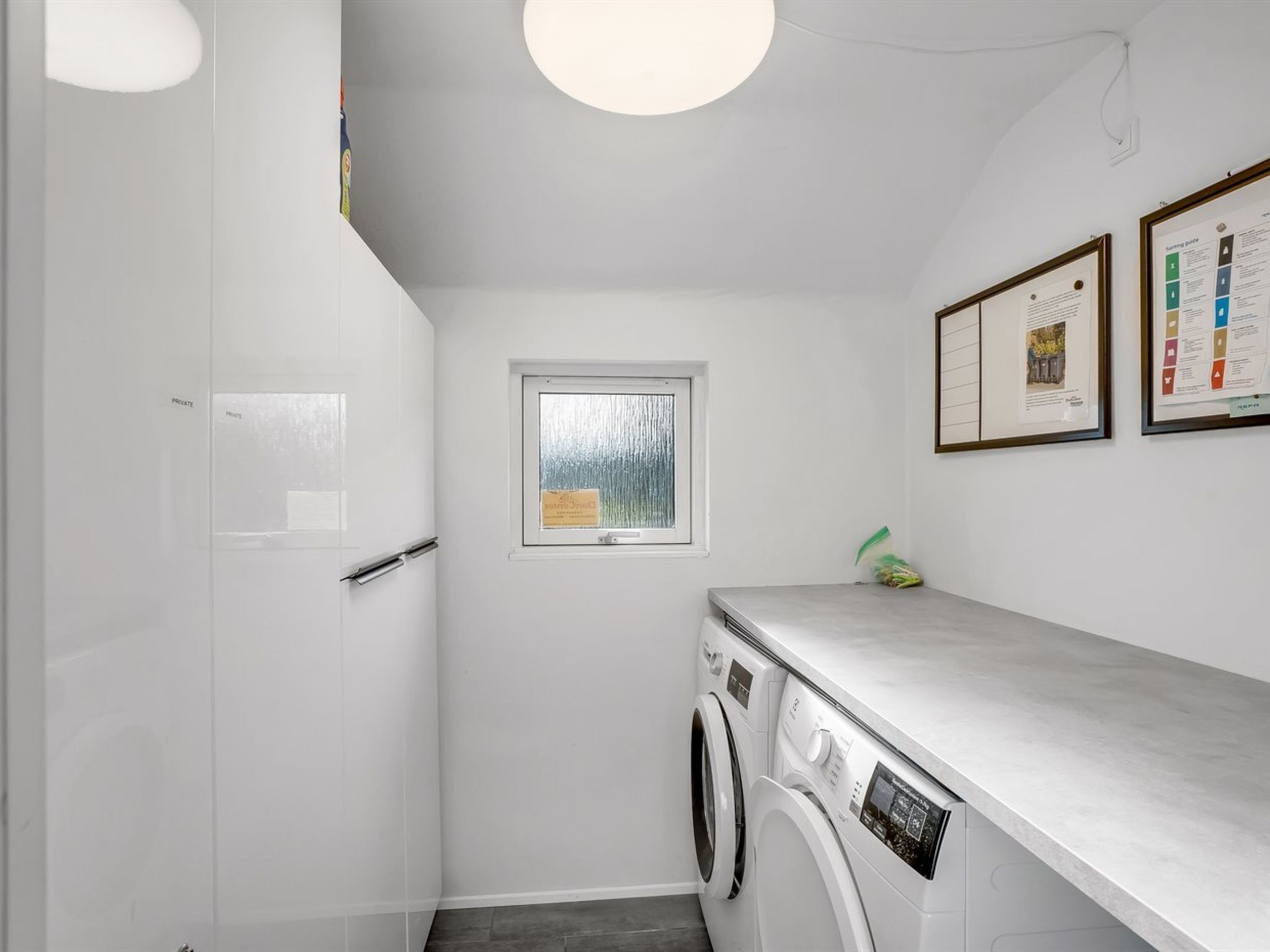 A compact laundry room with a washing machine, a drying rack, and a window.