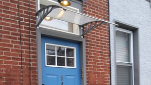 Une porte bleue avec une petite fenêtre, une boîte aux lettres et un luminaire au-dessus.