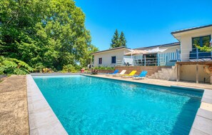 A swimming pool with clear blue water, surrounded by a patio area with lounge chairs and a building with a balcony. - Gorgeous home in Coursac (Coursac)