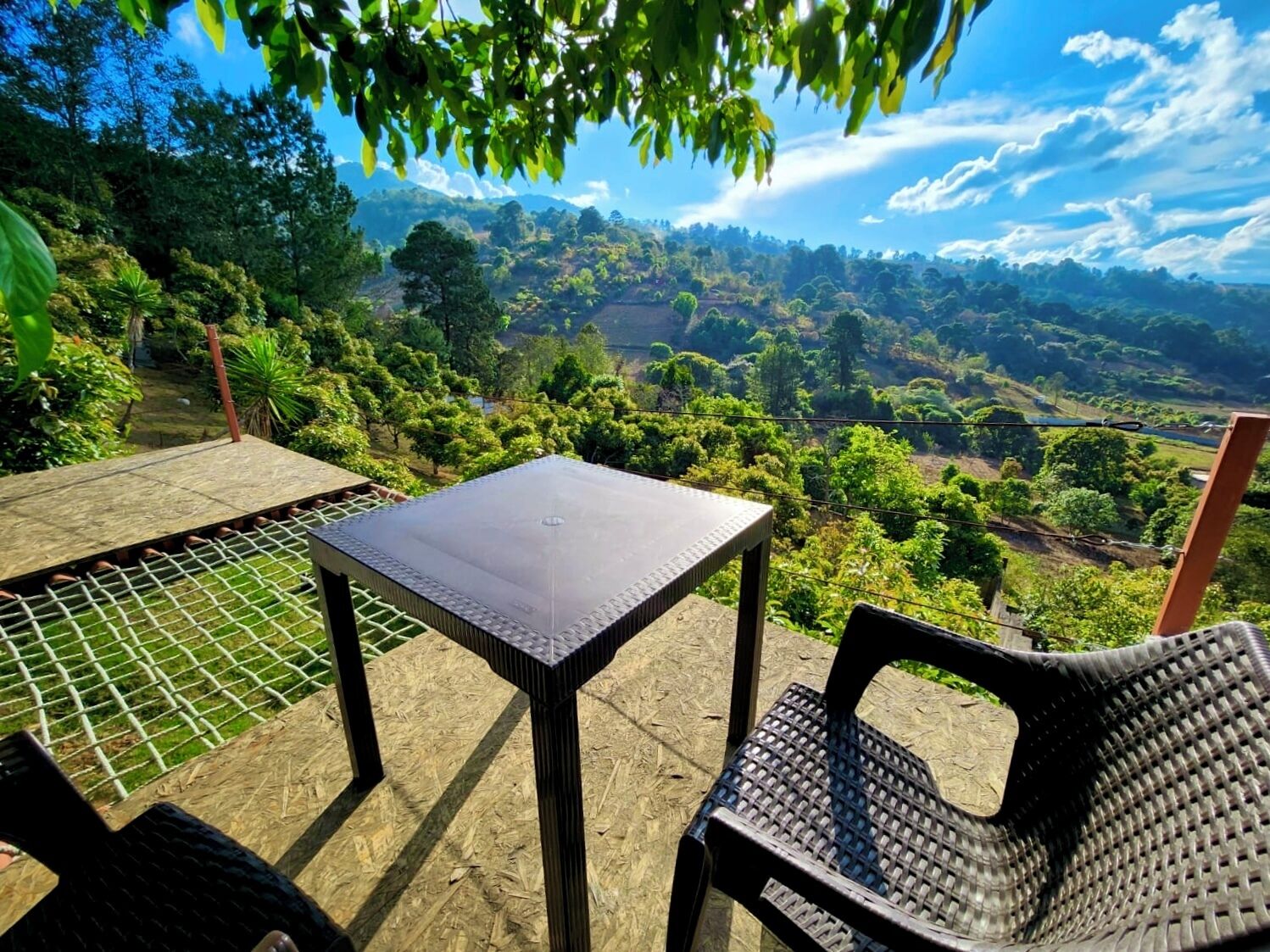 An outdoor seating area with a table and chairs, overlooking a lush landscape.