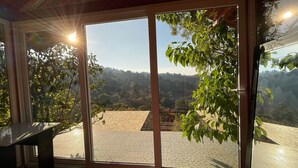 Ein Zimmer mit einer großen Schiebeglasdoor, die auf eine Terrassenanlage mit Blick auf eine hügelige Landschaft führt.