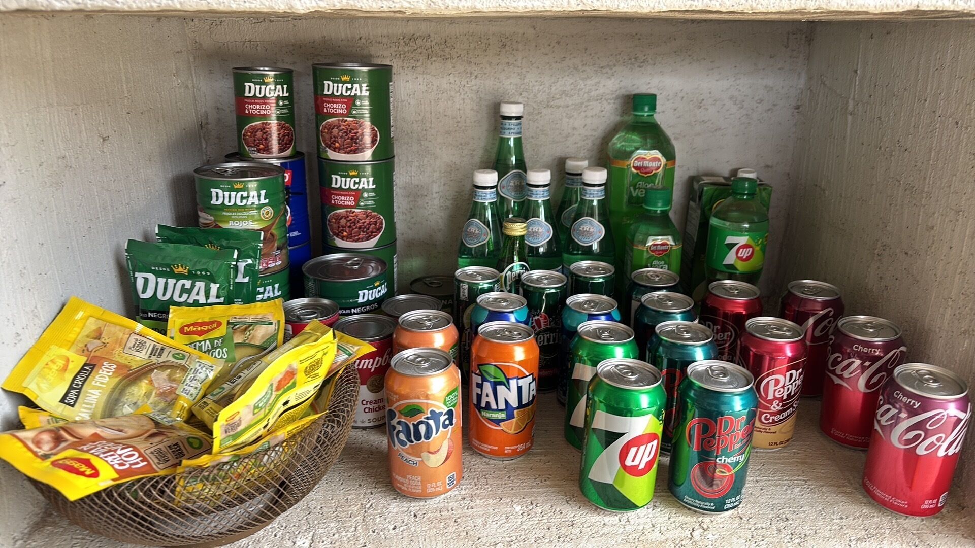A shelf stocked with various canned goods, bottled beverages, and snack packets.