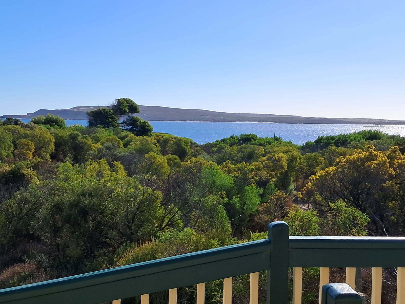 A coastal landscape with dense greenery and a clear view of the sea.
