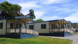 A row of mobile homes with a porch and steps, surrounded by grass and trees. - Elliston Waterloo Bay Tourist Park  (Elliston)