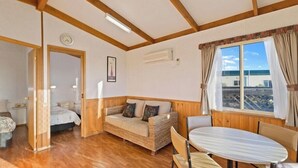 A cozy room with a wooden ceiling, a sofa with cushions, a round table, and a window with curtains. - Elliston Waterloo Bay Tourist Park  (Elliston)