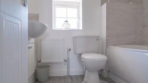 A bathroom with a toilet, a bidet, a bathtub, a window, and a radiator. - Sleeps 5 - Private Garden- Free Parking (Corby)