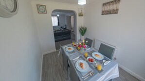 A dining area with a table set for breakfast, including croissants, fruit, and orange juice. - Sleeps 5 - Private Garden- Free Parking (Corby)
