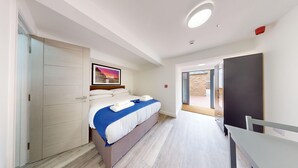 Une chambre d’hôtel moderne, équipée d’un lit, d’un bureau et offrant une vue sur l’extérieur.