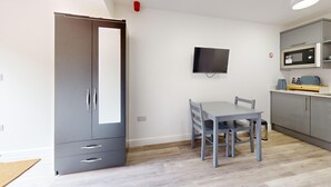 Une cuisine moderne avec des meubles gris, un four à micro-ondes encastré et un petit coin repas comprenant une table et des chaises.