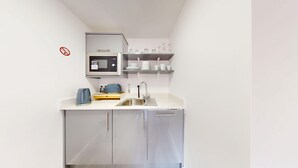 Une cuisine compacte équipée d’un four à micro-ondes, d’une bouilloire et d’un évier.