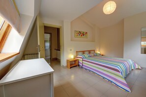 Une chambre à coucher avec un lit, des tables de chevet, une fenêtre et un radiateur.