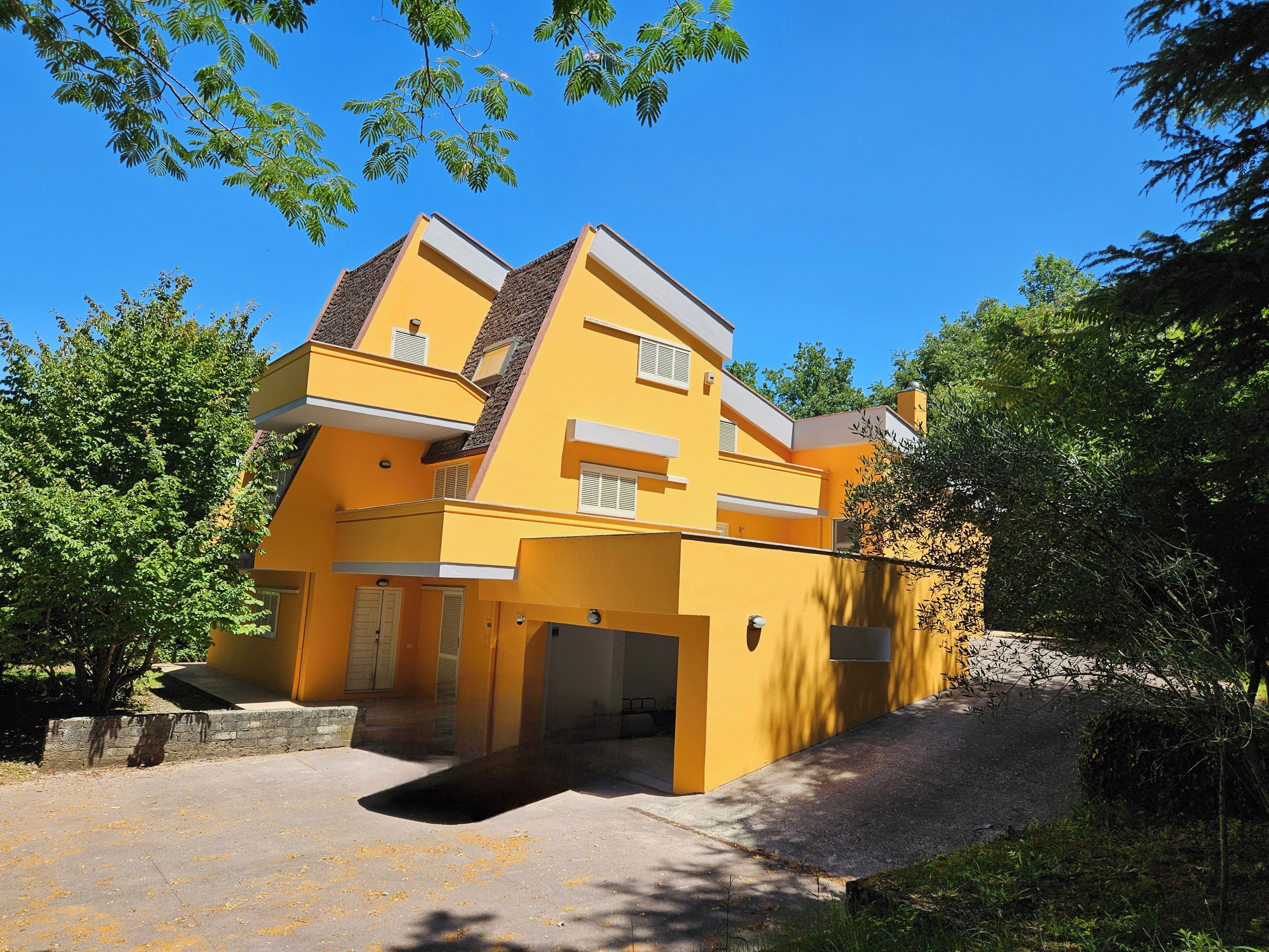 Un bâtiment moderne de couleur jaune, doté d’un toit plat, de grandes fenêtres et d’une entrée de garage bien visible.