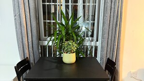 Una mesa de comedor con sillas, una planta en maceta y una ventana con cortinas.