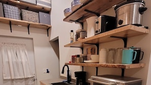 Una cocina compacta con muebles de madera, lavavajillas integrado, microondas y cafetera.