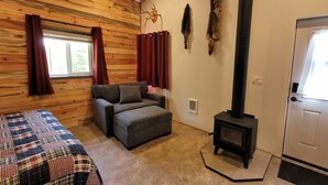 Una habitación acogedora con cama, sofá, chimenea y una puerta.
