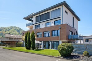 Un bâtiment moderne à deux étages, doté d’un balcon, de grandes fenêtres et d’une pelouse bien entretenue.