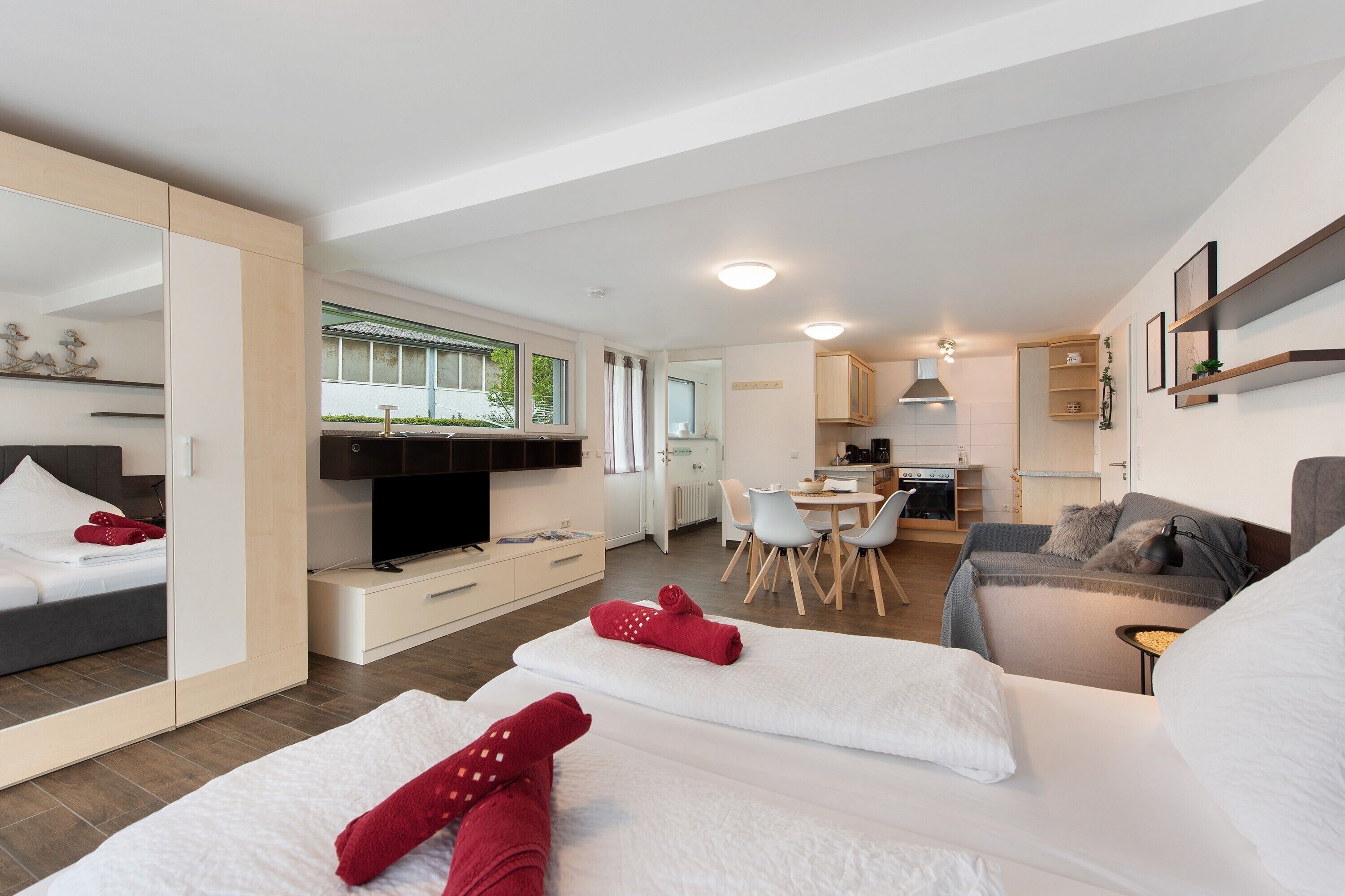 A modern hotel room with a bed, a sofa, a dining area, and a kitchen.