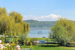 Eine friedliche Uferlandschaft mit Weidenbäumen, einer Bank und einer Wasserradstation.