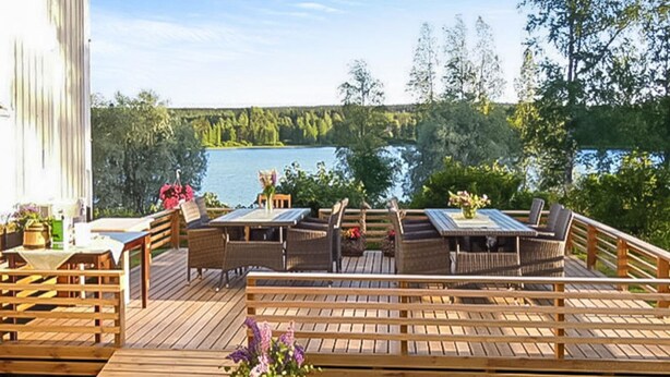 A wooden deck with outdoor furniture, a table, and chairs, overlooking a lake. - Vacation home Jutila by Interhome (Jämijärvi)