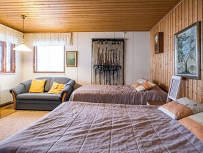 Una habitación con dos camas, un sofá y techo de madera.