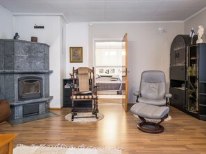Una sala de estar con chimenea, una silla de madera, un sillón moderno y una estantería.