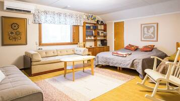 A cozy bedroom with a bed, a sofa, a rocking chair, a small table, and a bookshelf.
