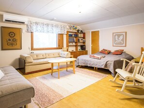 A cozy bedroom with a bed, a sofa, a rocking chair, a small table, and a bookshelf.