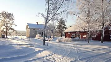 A snow-covered landscape with a house and a red barn.