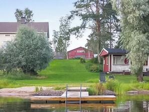 A lakeside property with a dock, a red building, and a house with a porch.