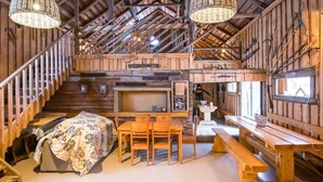 A rustic cabin interior with a wooden staircase, a dining area with a table and chairs, and a large window. - Vacation home Jutila by Interhome (Jämijärvi)