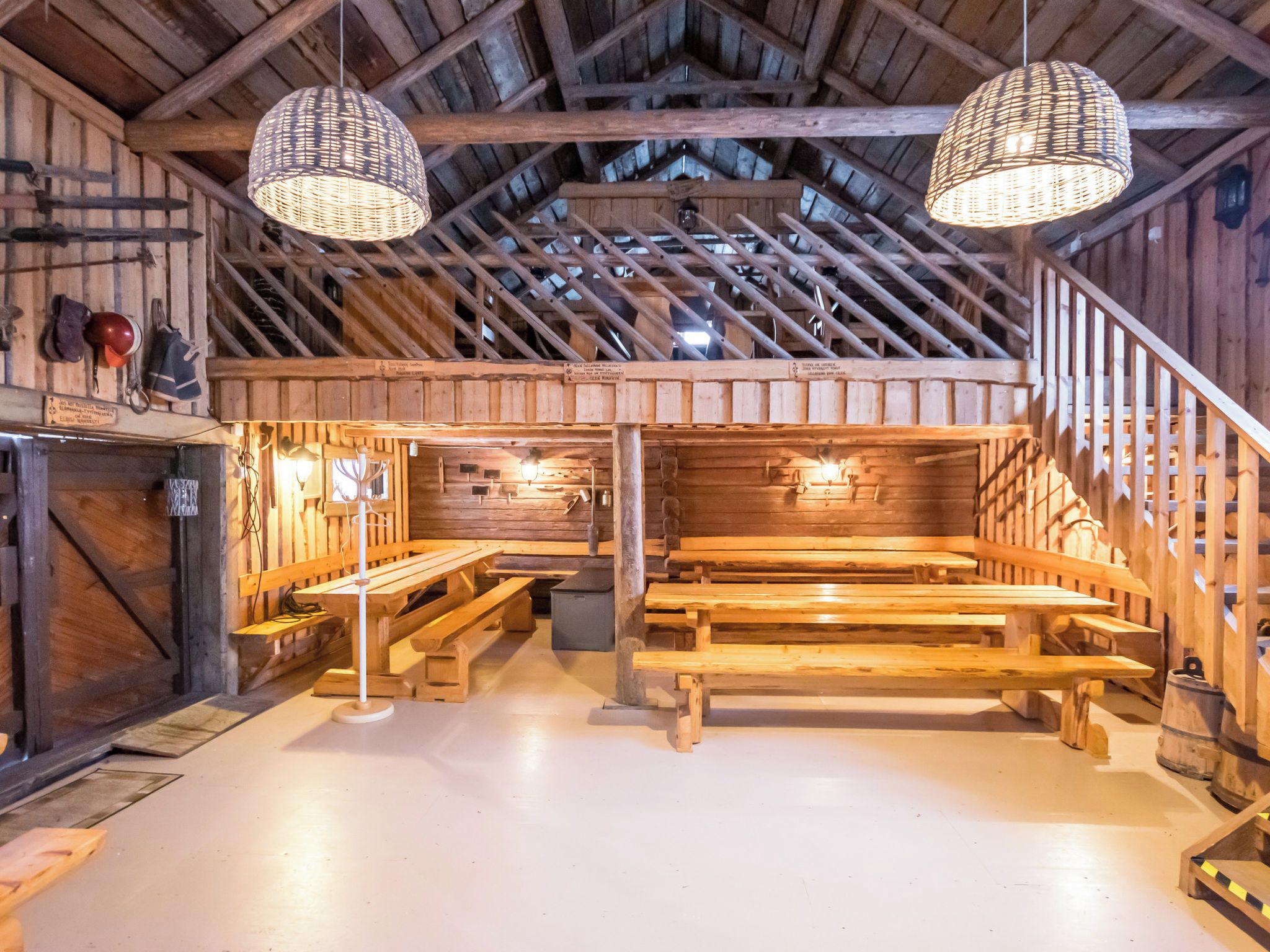 Ein rustikaler Holzinnenraum mit hohen Decken, Holzbänken und hängenden Lampen.