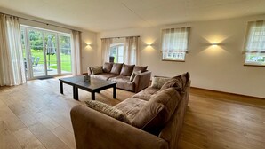 A spacious living room with a large sofa, a coffee table, and a sliding glass door leading to a patio.