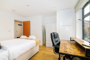Una habitación de hotel con cama, escritorio, silla y ventana.