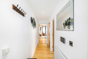 A hallway with a coat rack, a wall-mounted mirror, and a thermostat. - Shoreditch Hoxton 2BR, 2 Bath, Terrace Sleeps 6 (Greater London)