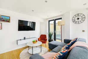 Ein modernes Wohnzimmer mit Flachbildfernseher, einer Couch, einem Couchtisch und einer großen Wanduhr.