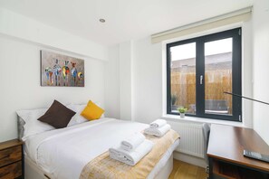 A hotel room with a bed, a painting, a window, and a desk. - Shoreditch Hoxton 2BR, 2 Bath, Terrace Sleeps 6 (Greater London)