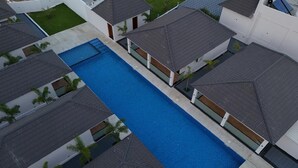 An aerial view of a residential area with a swimming pool surrounded by houses with sloped roofs. - DEE COTTAGE (Nagercoil)